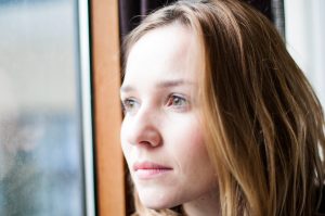 woman standing by a window looking outside